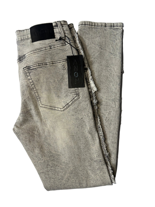 Alternate back layout of AMNÉ modern streetwear denim jeans in a textured grey acid wash. Displays heavily distressed frayed side seams, a signature black leather logo patch, and branded hang tags.