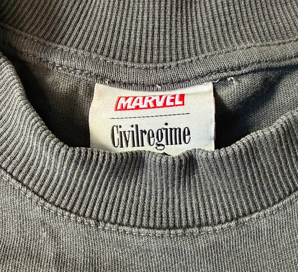 Close-up of a gray ribbed knit garment neck label reading Marvel and Civilregime.