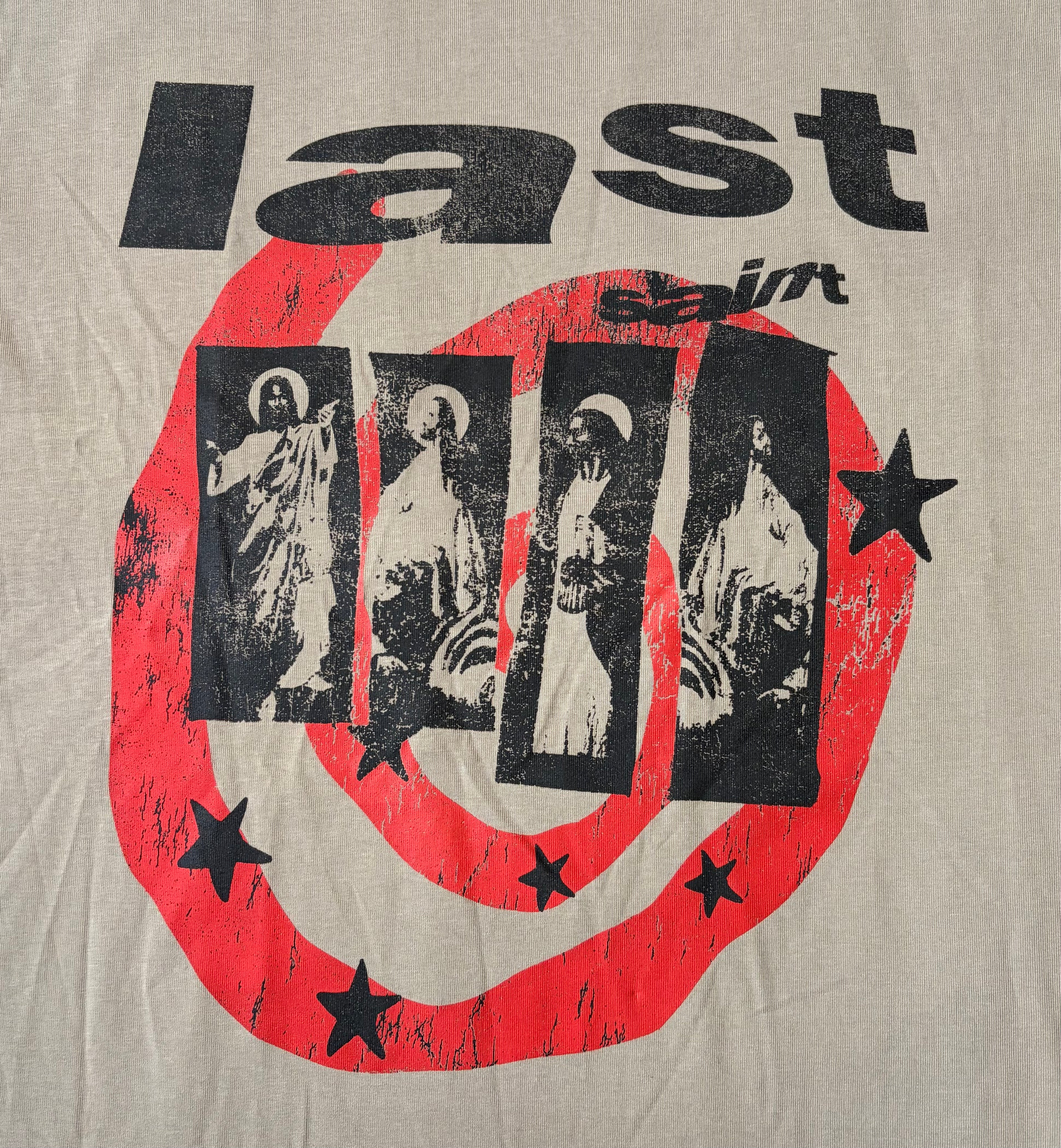 A close-up of a beige graphic print featuring the word 'last' in distressed black lettering above a large red circular design with black stars and four vertical black panels containing religious figures.