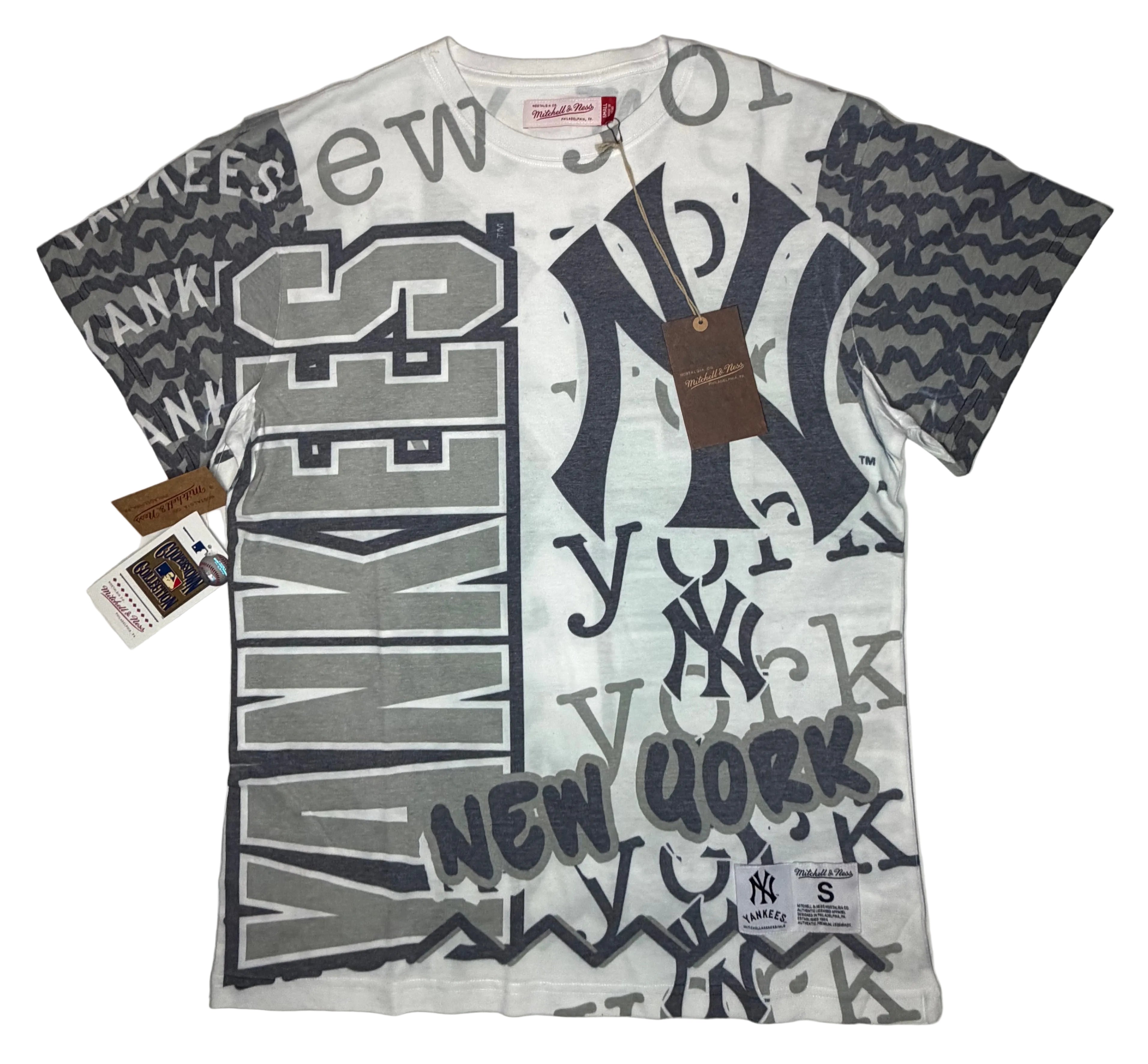 Mitchell & Ness New York Yankees White Jumbotron 2.0 all-over sublimation print T-shirt featuring a crowded multi-font collage of team logos, wordmarks, and typography.