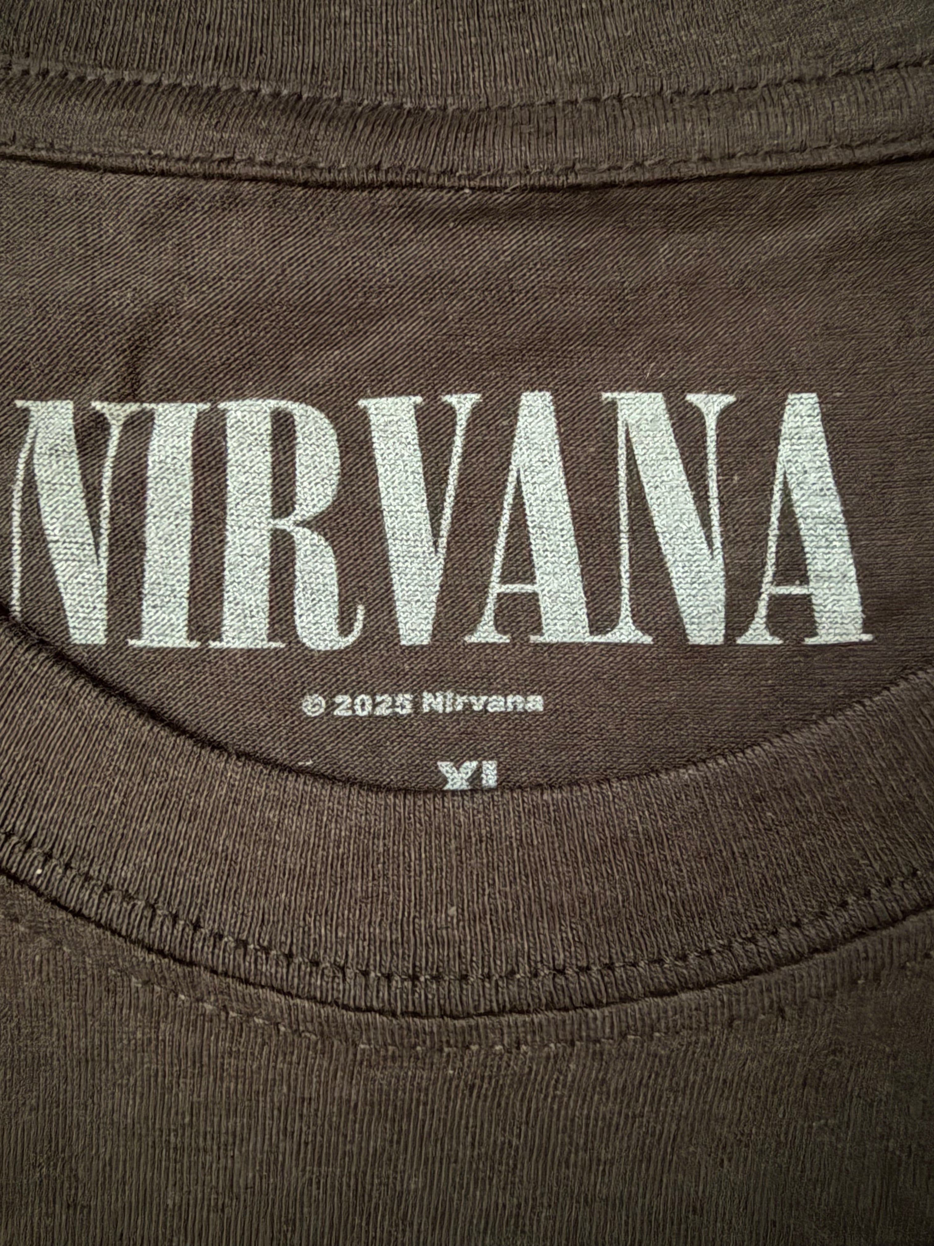 Close-up of the screen-printed inside neck collar of the official black Nirvana unisex t-shirt, showing the white distressed band logo and copyright branding detail.