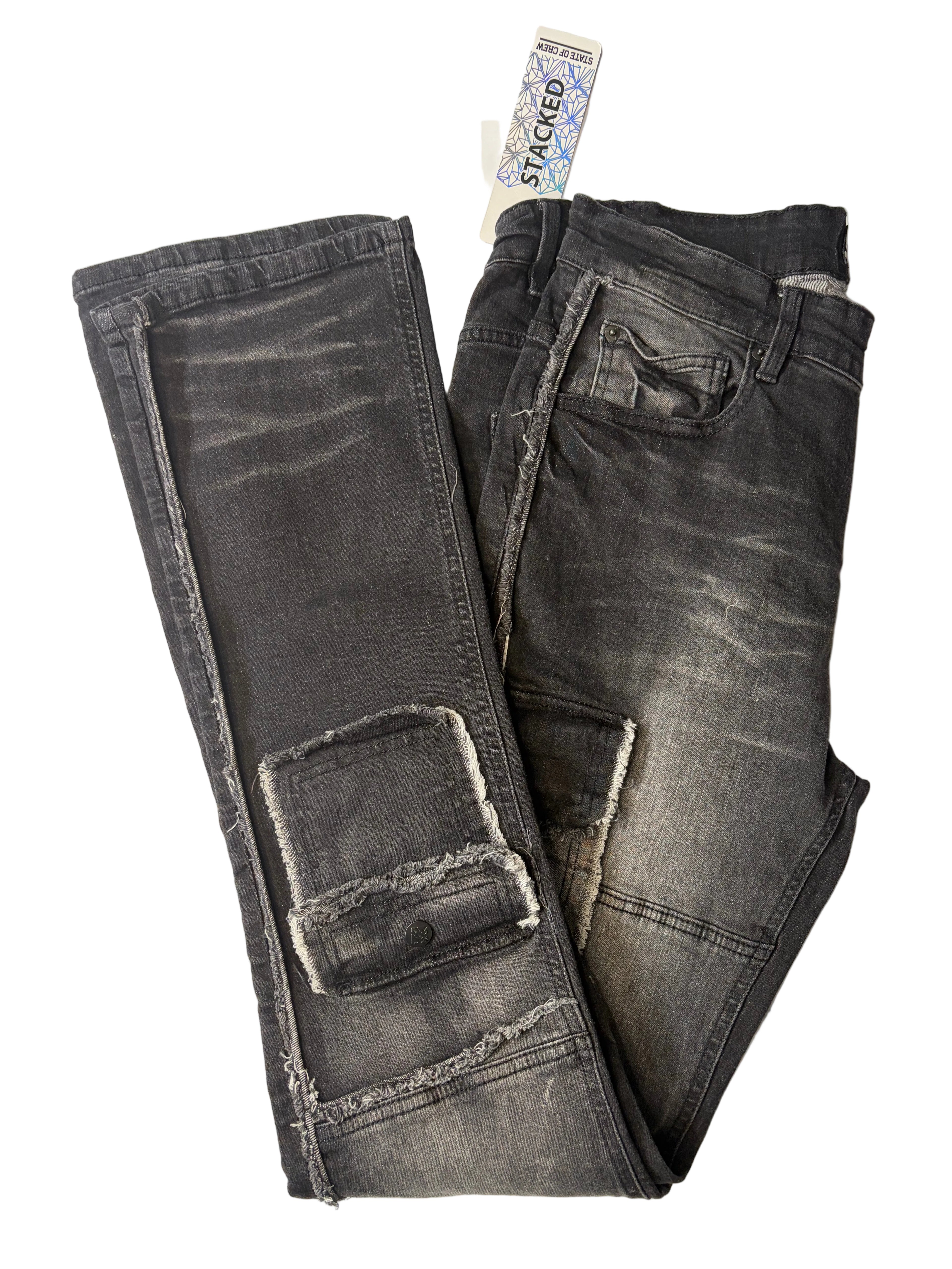 Alternate product view of Stacked modern streetwear cargo jeans in faded black charcoal denim. Displays distressed raw-edge accents, lower leg utility cargo pockets, heavy whiskering textures, and a white brand tag.