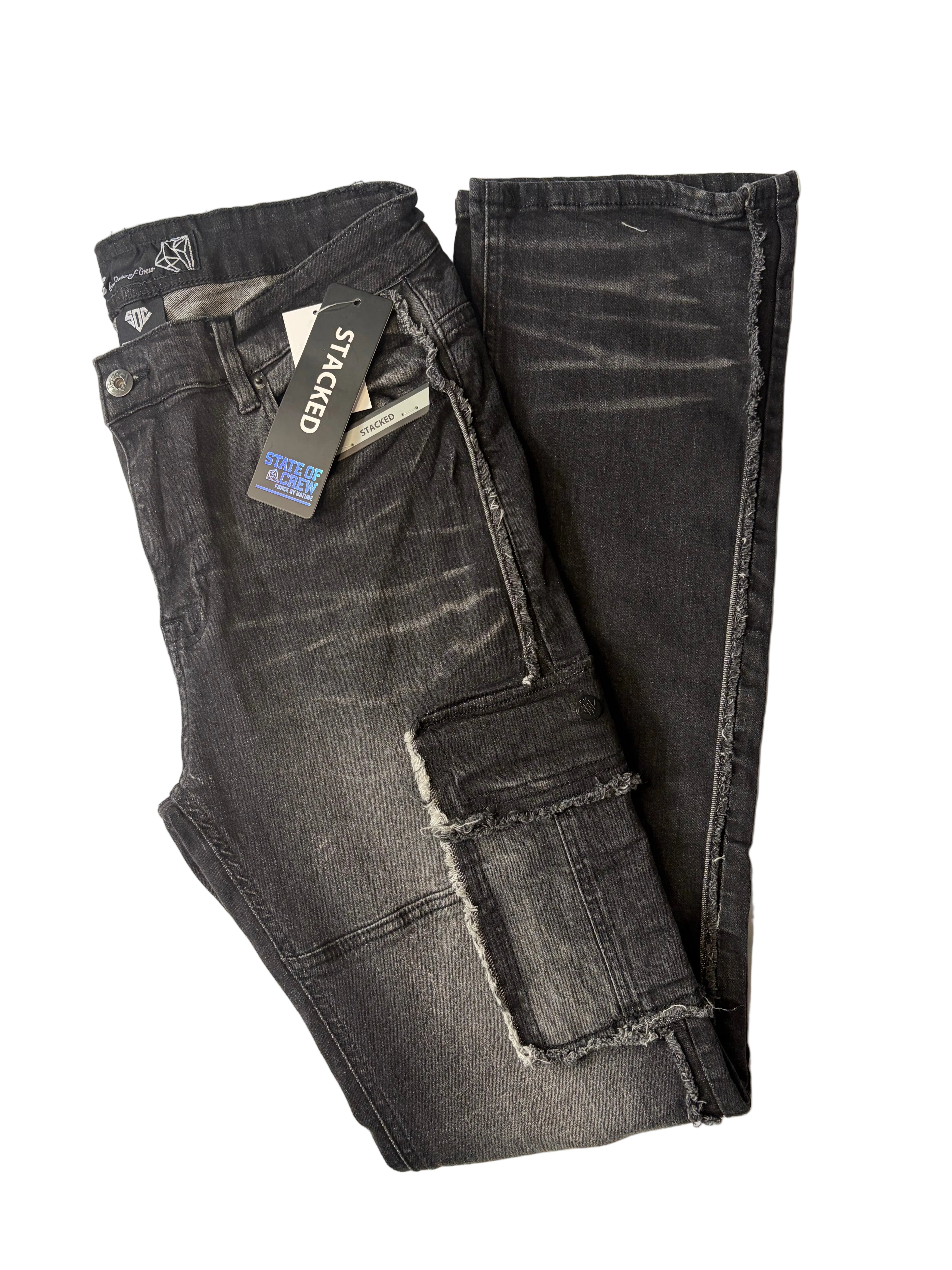 Stacked modern streetwear cargo jeans in a washed black charcoal denim finish. Features raw, frayed edge detailing, utility thigh pockets, a relaxed stacked leg silhouette, and original brand hang tags.