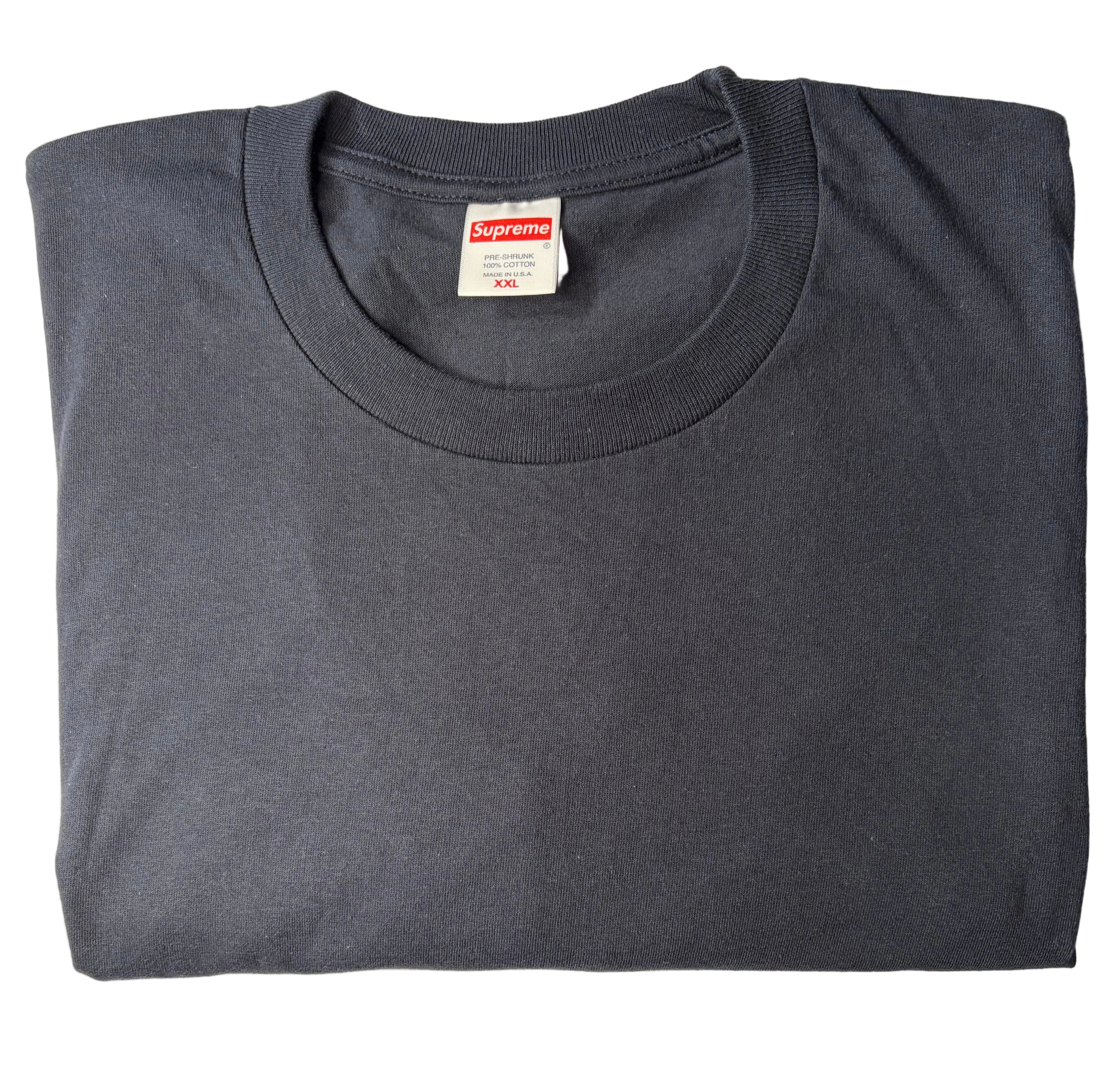 A folded dark gray crewneck t-shirt with a Supreme box logo tag visible inside the collar, laid flat on a white fabric background.