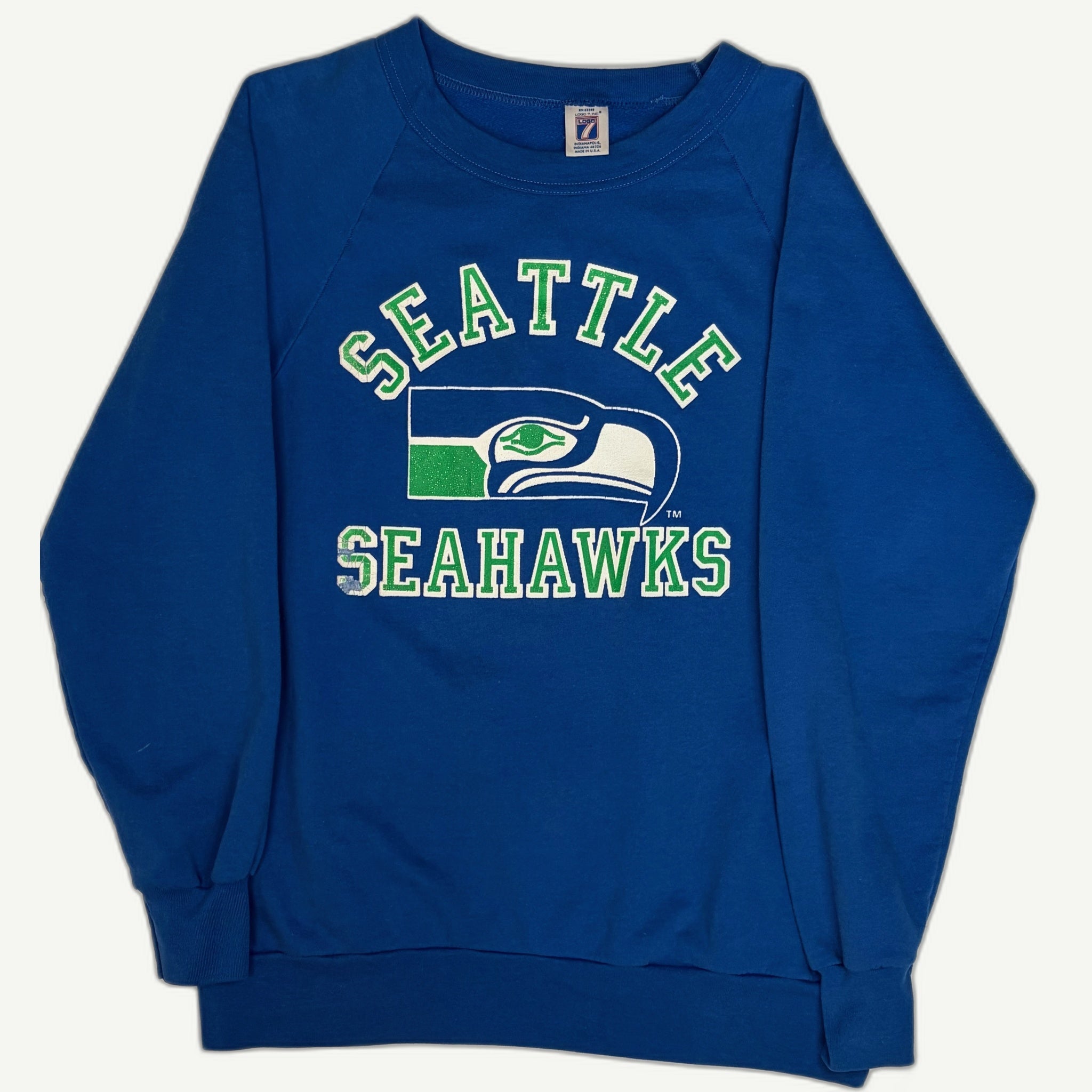 Vintage 1980s Seattle Seahawks royal blue crewneck sweatshirt featuring an arched varsity spellout and a throwback hawk head logo.